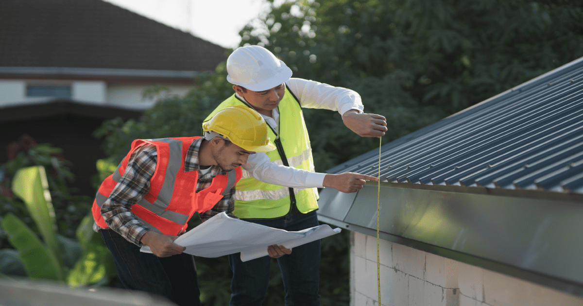 Dakwerkers inspecteren het dak om offertes voor de dakwerken te bepalen.